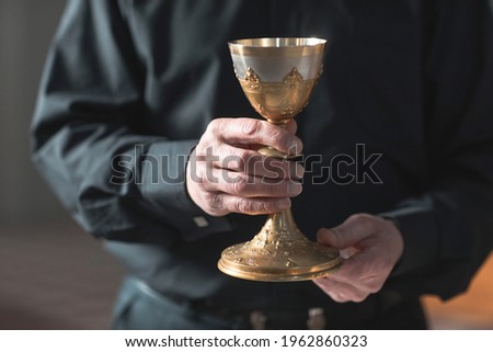 Close-up of senior priest holding the cup in the church Royalty-Free Stock Photo #1962860323