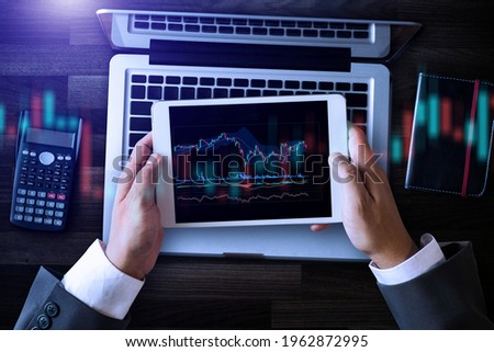 Top view business working at modern office.Technical price graph and indicator, red and Blue candlestick chart and stock trading tablet and computer
