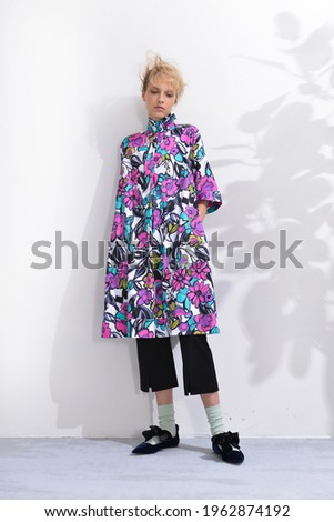 Fashion model Posed on with a shadow green leaves
background in fashion clothes on studio

