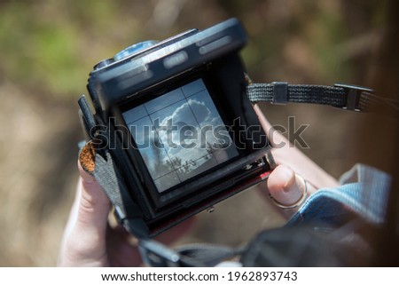 An overhead view of hands holding a medium format retro film camera. Close-up