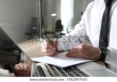 Businessman working with documents at wooden desk in office, closeup