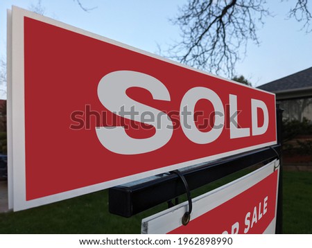 Fresh new sign sold in front of detached house in residential area. Real estate bubble, crash, hot housing market, overpriced property, overpaid, buyer activity concept. Selective focus.