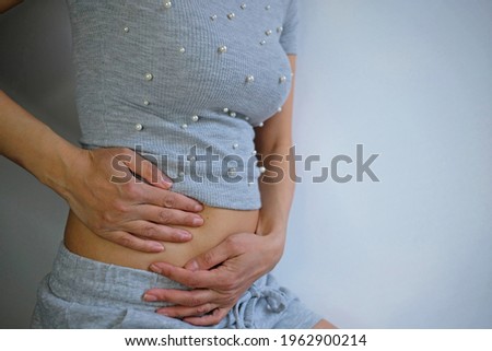 Hands on bally indicating health problems such as appendicitis, abdominal pain, gut problems, women's health problems, pregnancy or immune problems. Background is white, in the picture is woman.
