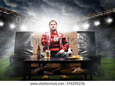 happy soccer or football fan with hand on heart on sofa at stadium Royalty-Free Stock Photo #196290236