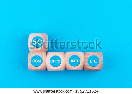 A top view of wooden cubes with 5G and other mobile network technology signs on blue background