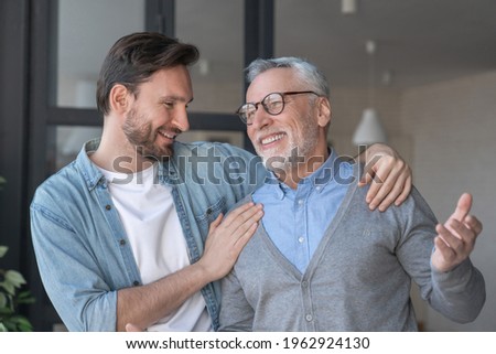 Young adult caucasian son listening and supporting his old elderly senior father at home indoors.Happy father`s day! Care and love concept. I love you, dad! Royalty-Free Stock Photo #1962924130