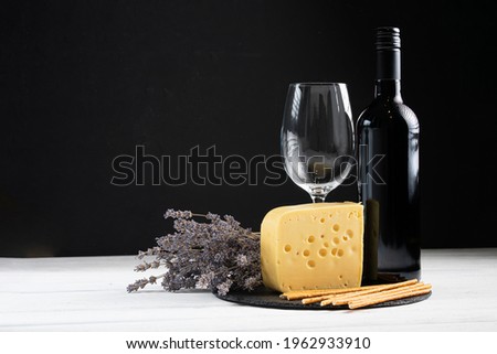 Bottle of red wine with label on old board. Glass of wine and cork