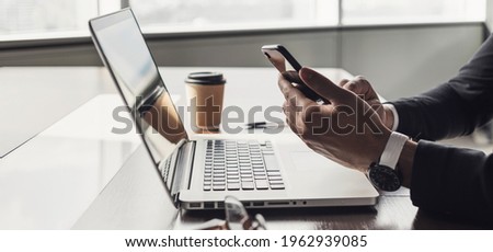 Businessman using smart phone working on laptop computer in the office. Male hands holding mobile phone. Internet marketing, entrepreneur, business, finance, management, finance, new business concept