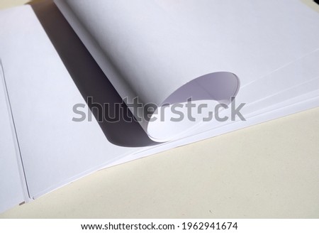A large stack of white paper on a light background. Paper shadows.