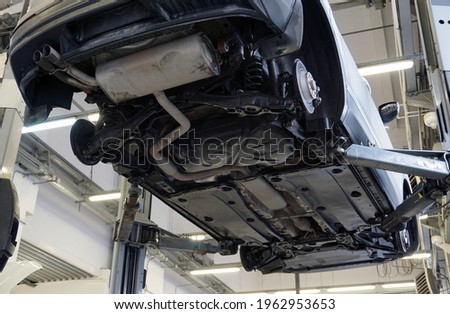 Modern car in a car service. Bottom view. The underside of the car, suspension and exhaust system elements. Car service and spare parts. Royalty-Free Stock Photo #1962953653