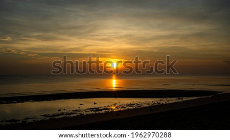 beautiful sunrise on the morning at the beach with orange sun and many cloudy 