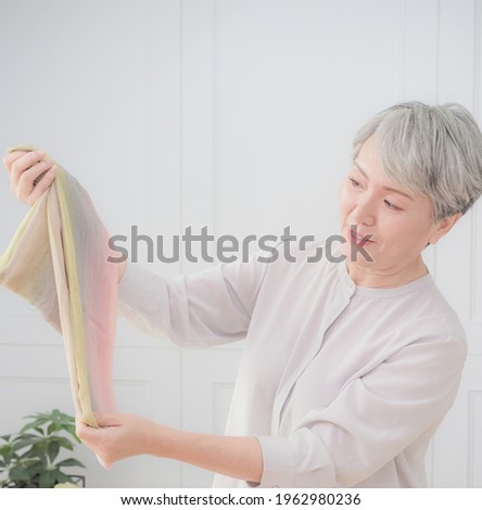 Senior Asian woman receives scarf and show it.