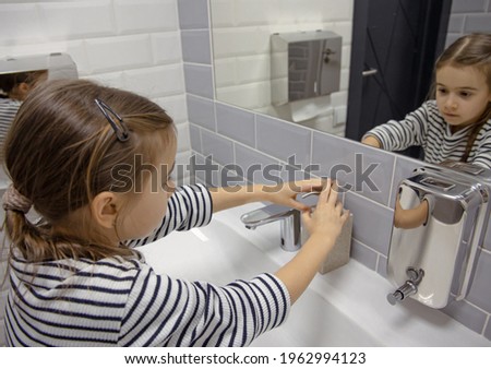 Little girl uses liquid soap to wash her hands. Hygiene and cleanliness in a coronavirus environment.