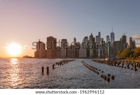 Beautiful Sunset and Lower Manhattan skyline with East River and New York City. Twilight with Reflections and Abandoned Pier at Sunset from Brooklyn Bridge Park
