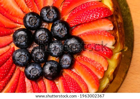 Closeup and zoom out pictures of a Basque burnt cheesecake focusing on the strawberries and blueberries used as garnish.