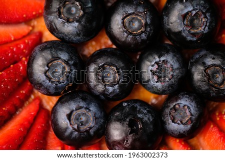 Closeup and zoom out pictures of a Basque burnt cheesecake focusing on the strawberries and blueberries used as garnish.