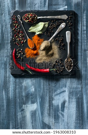 Set of various spices on black cutting board and blue wood background with space for your text. Top view.