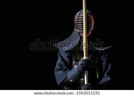 Japanese kendo fighter with with shinai on a black background Royalty-Free Stock Photo #1963015195