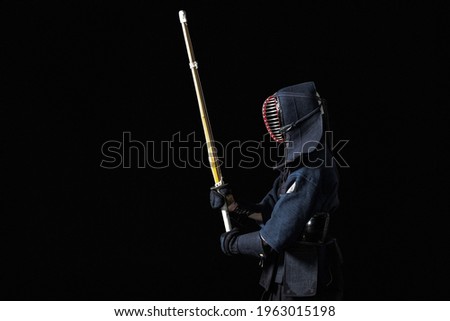 Kendo fighter with with shinai on a black background Royalty-Free Stock Photo #1963015198