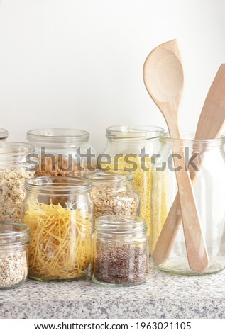 Variety of cereals, grains, pasta, seeds in glass jars uncooked on white kitchen background, closeup, zero waste, eco friendly, balanced diet food, healthy clean eating concept, vertical Royalty-Free Stock Photo #1963021105