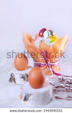 Easter cake in a festive package on a light background. Willow branches.Easter holiday. Free space. Chicken eggs on wooden stands. Vertical photo.