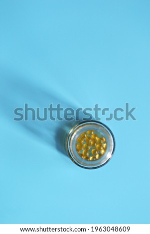 Vitamin D and Omega 3 fish oil capsules supplement. Yellow capsules, tablets or pills. Blue background. Copy space
