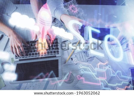 Double exposure of man and woman working together and SEO hologram drawing. Search engine concept. Computer background. Top View.