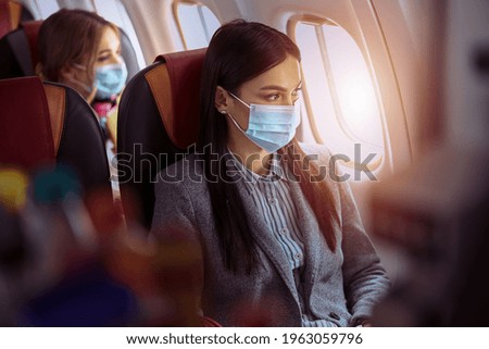 New order in airplane. Woman is sitting in mask before fly Royalty-Free Stock Photo #1963059796