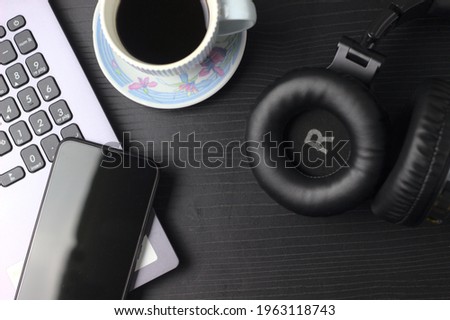 computer, cell phone, headphones, coffee on black background
