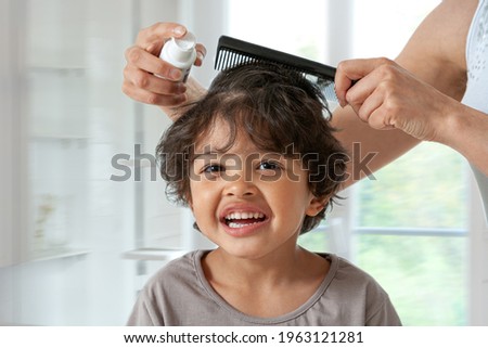 Mother treating  son's hair against lice. Head lice treatment for schoolchild.