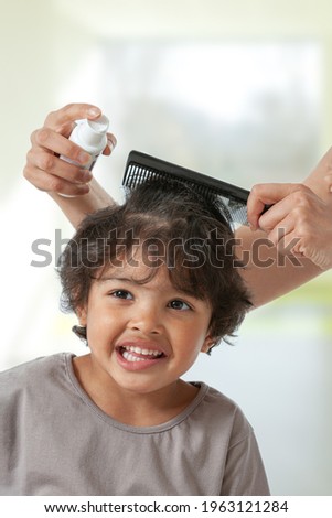 Mother treating son's hair against lice. Head lice treatment for schoolchild.