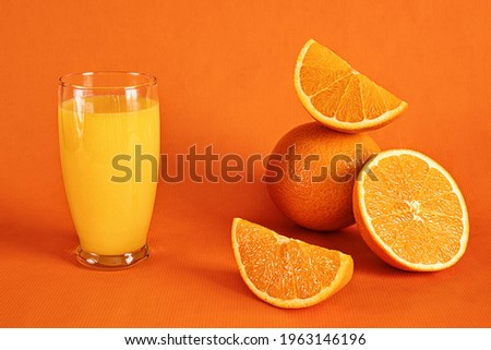 Fresh orange juice in glass and orange slices.Orange background.Monochromatic food photography.