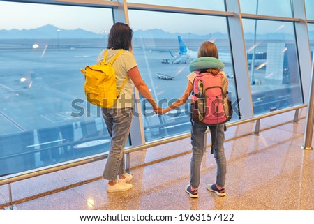 Airport passengers family mother and daughter child looking at planes in panoramic window