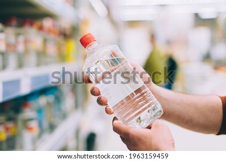 A man in a hardware store holds a bottle of solvent Royalty-Free Stock Photo #1963159459