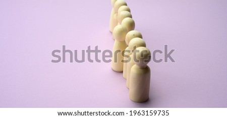 wooden men stand in a row, one figurine sticking out in front. The concept of exclusivity, talent