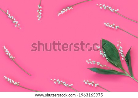 Flower arrangement of white sprigs of lily of the valley on pastel pink background. Spring nature concept. Creative layout.