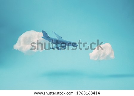 A blue passenger plane maneuvers between large clouds. Travel and transportation concept.