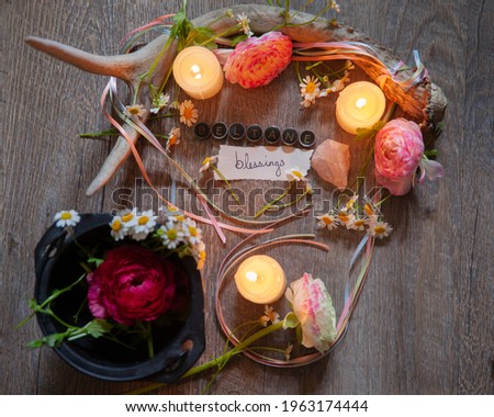 A pagan altar set for the Mid-Spring Holiday: Beltane.  The altar features deer antler, candles, pastel ribbons, chamomile and Ranunculus blooms, and the message "Beltane Blessings."