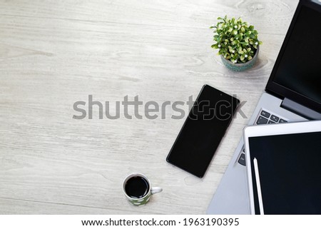 Wood office desk with computer, mobile phone, tablet, tablet pen, coffee and plant