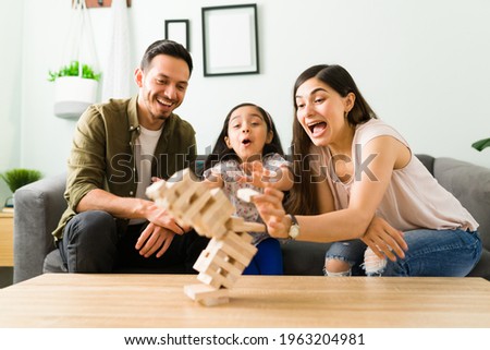 Surprised family laughing while losing a board game after a wooden stack falls down in their living room table