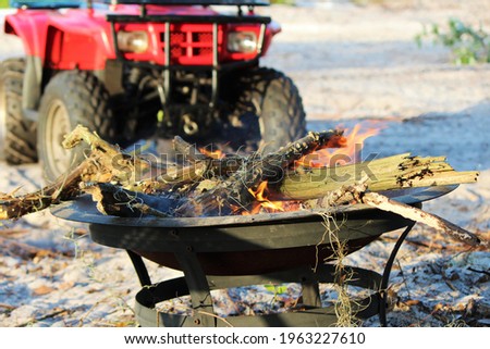 Selective focus on campfire with atv in the background at a camp site.