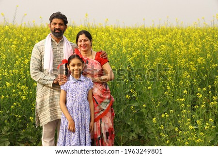 Indian happy rural family in mustard filed  Royalty-Free Stock Photo #1963249801