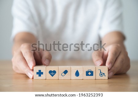 Hand holding wooden block arranging on wood table with icon healthcare medical, Insurance for your health concept