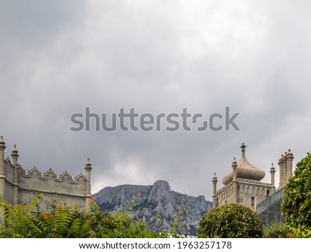 The walls and towers of the old palace on the background of high mountains and cloudy sky. Vorontsov Palace is a historic palace situated at the foot of the Crimean Mountains near town Alupka, Crimea.