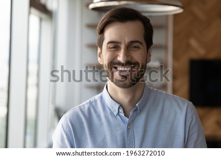 Profile picture of happy millennial 20s Caucasian man stand pose in modern office workplace. Headshot portrait of smiling young male employee or worker feel optimistic. Employment, hr concept. Royalty-Free Stock Photo #1963272010