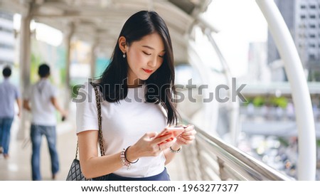 Business people shopping via online application media concept. Happy smile young adult asian woman consumer using creadit card and smartphone. City on day background with copy space. Royalty-Free Stock Photo #1963277377