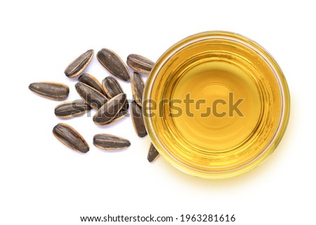 Glass bowl of sunflower seed oil and fresh organic sun flower seeds isolated on white background. Top view. Flat lay.