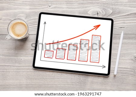 Bar chart drawing on the screen of tablet computer showing positive growth trend