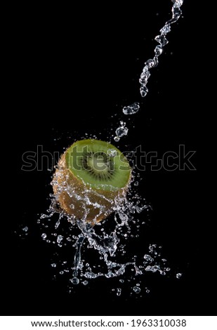 Kiwi fruit with water splash flying in the air isolated on black background