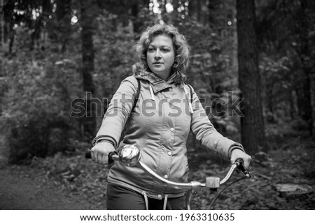 Blond woman with bike in the woods. Black and whait photo.